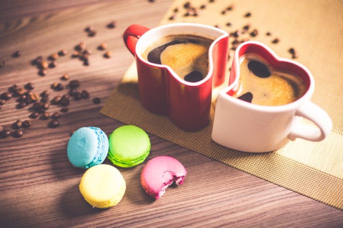 zwei herzförmige Tassen und Macarons